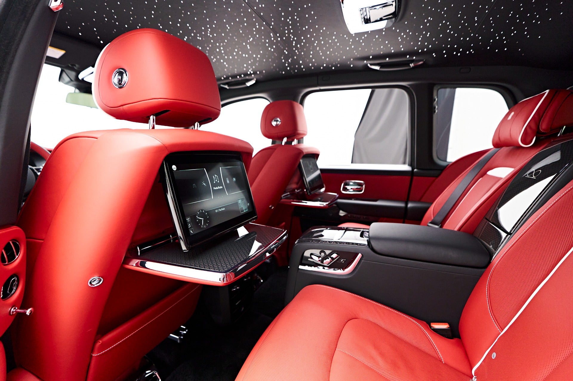 Luxury exotic car interior with premium red leather rear seats and screens